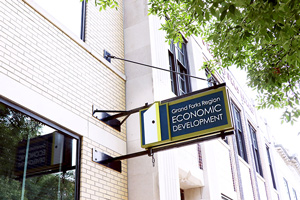 The Grand Forks Region Economic Development Corporation's sign on the sign of the building with a tree hovering over it.