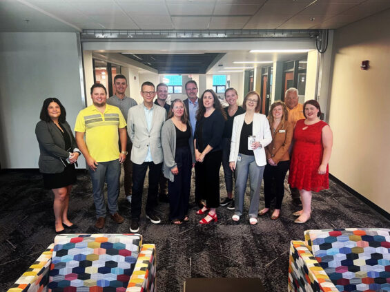 A group of City of Grand Forks Staff and Grand Forks Region EDC staff stand with EDA representative Ali D in The HIVE building in Downtown Grand Forks.