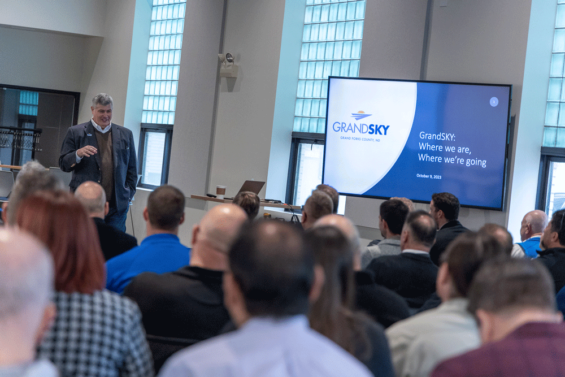 Tom Swoyer stands and presents in front of a group of business leaders at the HIVE.