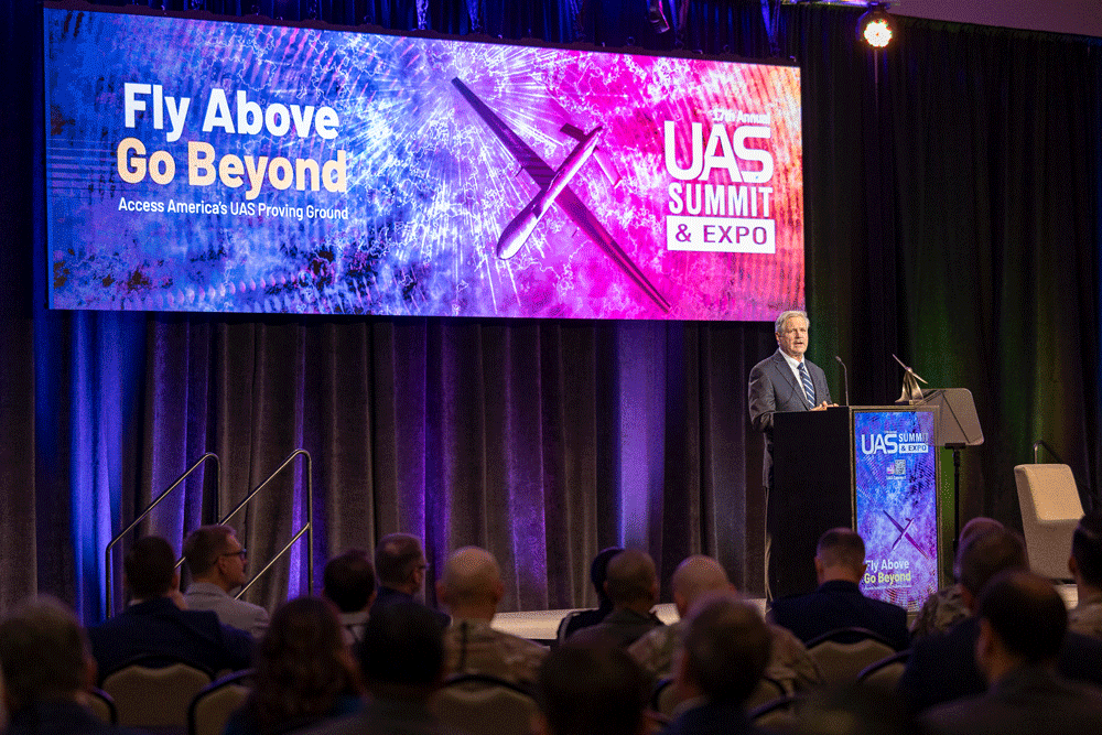 On the main stage of the UAS Summit and Expo, Senator John Hoeven addresses a crowd of attendees expressing the impact of Grand Forks on the UAS industry.