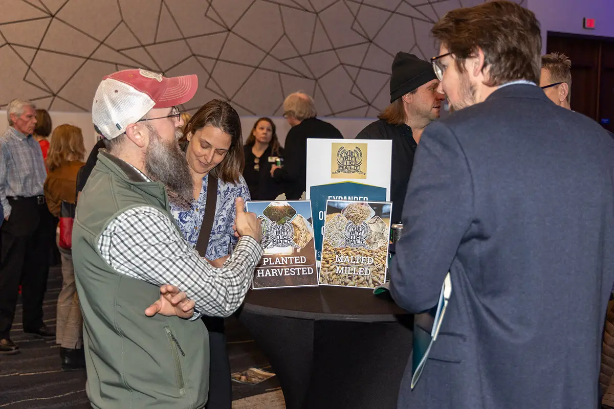 Vertical Malt staff stand talking to guests at the Annual Meeting.