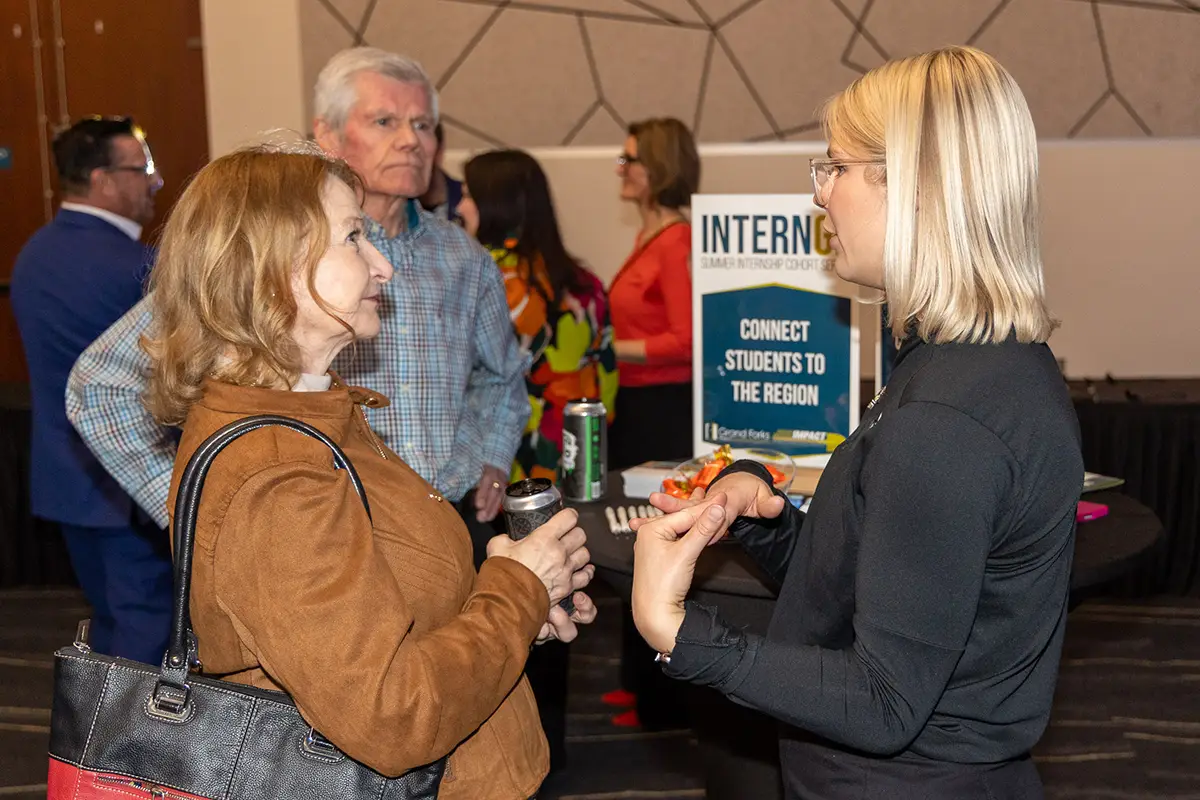 InternGF Staff stand at a cocktail table talking with guests at the 2026 annual meeting.