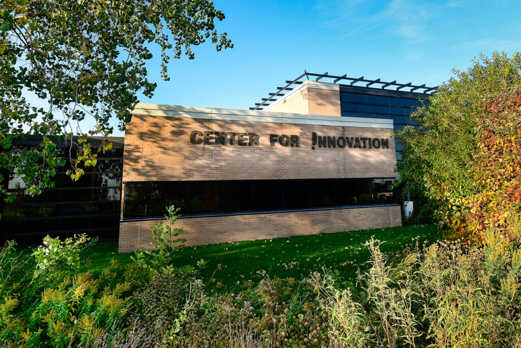 a building that is labeled center for innovation is positioned amongst foliage and trees