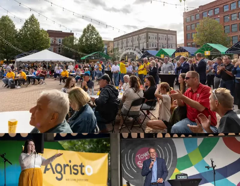 Community event in Grand Forks Town Square with speakers, Agristo banner, and large crowd gathered outdoors.